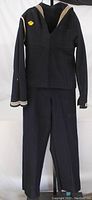 Full view of the WWII US Navy sailor uniform hanging on a rack showing both jumper and trousers