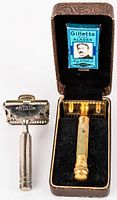 Photo of both vintage safety razors; one inside original Gillette brown case with blades, one silver-tone Star razor outside the case