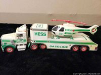 Side view of the toy truck connected to the trailer with the helicopter on the trailer bed