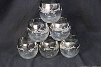 Front image of six round roly-poly cocktail glasses stacked showing the silver mirrored rims with etched floral pattern around upper portion of each glass.