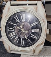Front view of square wall clock with Roman numerals and distressed white frame, showing clock face and hands.