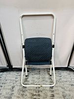 Front view of the closed 2-step foldable ladder showing white metal frame and black step surfaces.