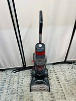 Front view of Bissell ProHeat 2X Revolution Pet carpet cleaner showing the upright cleaner with clear water tanks and black/red design.