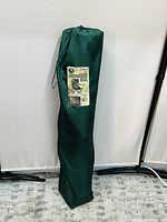 Foldable camping chair packed inside a green carry bag with label showing product details.