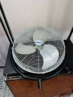 Front view of the industrial wall fan showing three metal blades inside a white protective grille with the Jackle brand at the center. The fan is mounted on a sturdy black metal frame.