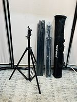 Full view of two adjustable tripod stands, two sets of rods in plastic wrapping, and the Neewer branded carrying bag standing upright.