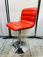 Side view of orange cushioned bar stool showing height adjustable metal base and footrest.