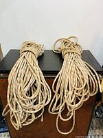 Two long coiled ropes on black and wooden surface, showing overall condition and length.
