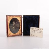 Full open view of the antique floral tooled leather photograph case showing the tintype portrait of a bearded man, the blue velvet lining, and a handwritten card identifying the subject as Roger Sherman Prescott.