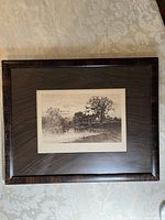 Framed etching showing a rural house near a pond in black and white, overall frame and matting visible.