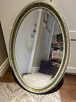 Front angle view of the oval mirror showing the frame and bevelled glass.