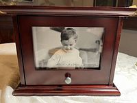 Front view of dark polished wooden photo box with a 6x4 inch photo in front frame and knob handle beneath.