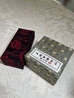 Two decorative fabric-covered boxes with intricate patterns, one labeled with Chinese characters