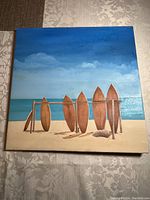 Front view of the 16x16 inch canvas painting showing surfboards on a beach with ocean background.