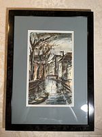 Full view of framed watercolor painting showing canal scene and reflections in water with boats and buildings, framed in black wood with gray mat.