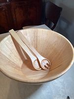 Top view of the wooden salad bowl with matching wooden salad servers inside the bowl, showing shape and finish.