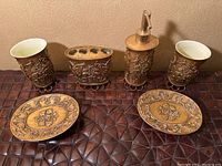 Front view of the gold bath accessory set with all six pieces aligned: 2 cups, toothbrush holder, soap dispenser, and 2 soap dishes.