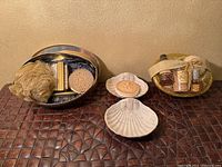 Full view of gold self care set with accessories, two shell soap holders, cherub soap, and gold basket with body care items.