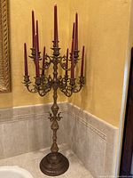 Full view of the tall brass candelabra with red candles, showing overall height and width.