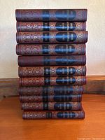 Stack of eleven encyclopedia volumes viewed from the spine showing the volume numbers and ornate spine design