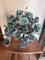 Full view of the green rose floral arrangement showing detailed petals, berries, and fish-shaped metal stand