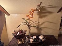 Three decorative items on surface: two potpourri bowls and an artificial orchid in a glass vase