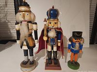 Front view of three wooden nutcrackers with distinct colors and costumes