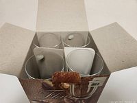 Top view of the open box containing four clear wine glasses in individual compartments, showing new condition and packaging.