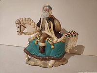 Left side view of hand painted ceramic Santa on horse figurine showing detailed paint and texture.