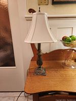 Table lamp off showing bronze-like decorative base and beige bell lampshade