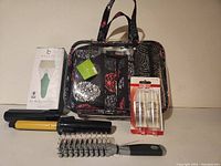 Photo showing Vera Bradley cosmetics organizer bag, ice roller packaging, Conair cordless curling iron, hair brush, and Conair heat protection spray.