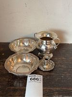 All four pieces displayed together: sugar bowl with lid at back right, pair of scalloped bowls at left, small candle holder front center