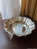 Front angle view of silver dish on wooden table with draped curtain backdrop