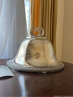 Domed lid on tabletop showing handle and engraving