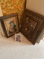 Photo showing all three religious icon artworks grouped on floor against wall with floral wallpaper.