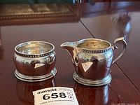 Creamer and sugar bowl on wood table with MaxSold lot tag