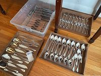 Wide view of trays and bin containing assorted flatware pieces.