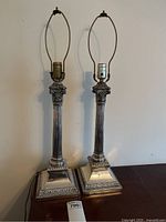 Full view of both matching silver column table lamps showing harp holders, fluted shafts, stepped square bases and lack of shades