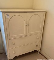 Front view of painted wood highboy with two cabinet doors and two drawers below.