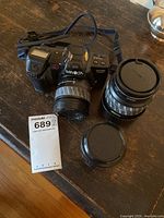 Top view of Minolta Maxxum 7000i camera with attached zoom lens, zoom lens extended, macro lens and third lens alongside on table