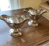 Pair of sauce boats on wooden surface, front angle view