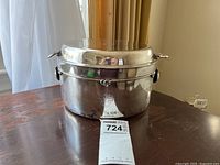 Full view of oval silver dish with lid on wooden table and tag visible