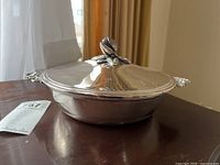 Angle front view of closed silverplate covered serving dish showing rose handle on lid and side handles