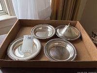 Four dishes and matching lid arranged in cardboard tray on tabletop under window light