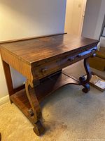 Full view of desk showing top surface, scrolled bracket legs and lower shelf
