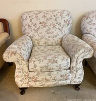 Front view of upholstered armchair showing floral fabric and rolled arms.
