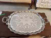 Entire tray on wood table showing full oval shape, handles and engraved surface