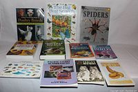 Photo of eleven animal-related books arranged on a flat surface, titles visible including Spiders, Poultry Breeds, The Big Bug Search, and more.