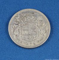 Close-up photo of the reverse side of the 1944 Canadian 50 cent coin showing the crowned shield of arms under a crown with two animals supporting the shield and text around the edge.