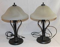 Pair of black metal base table lamps with frosted glass shades, showing full front view with cords and finials.